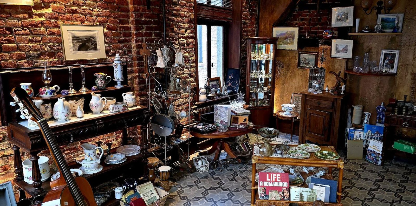 Intérieur de la petite boutique de la M.A.S : vaisselle ancienne, tableaux, livres et mobilier d’occasion sous les murs de briques